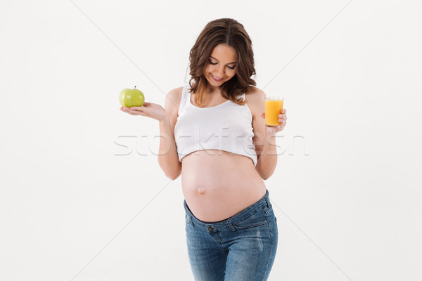 Happy pregnant woman drinking juice. Looking aside. Stock photo © deandrobot