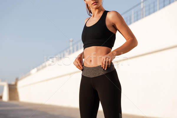 Cropped image of young fitness woman showing abs Stock photo © deandrobot