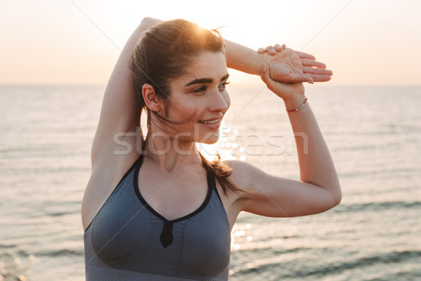 Smiling young sportswoman doing stretching exercises Stock photo © deandrobot