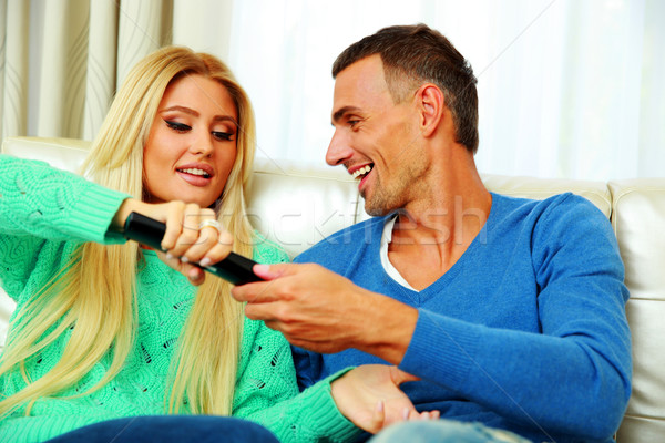 Happy couple bickering to change tv channel on remote control Stock photo © deandrobot