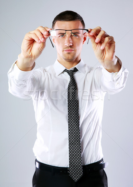 Businessmen holding glasses and looking through while over gray background Stock photo © deandrobot