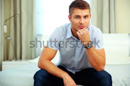 Serious handsome man sitting on the bed at home Stock photo © deandrobot