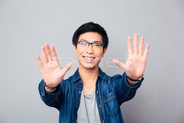 Happy asian man in glasses making stop gesture Stock photo © deandrobot