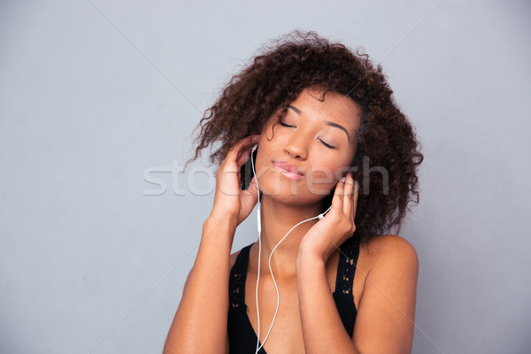 Afro american woman listening music in headphones Stock photo © deandrobot