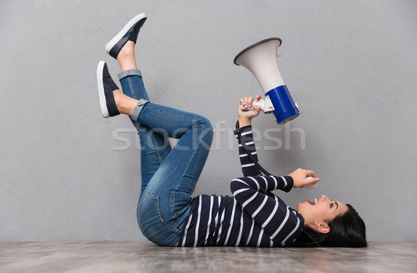 Young woman lying and speaking in megaphone Stock photo © deandrobot