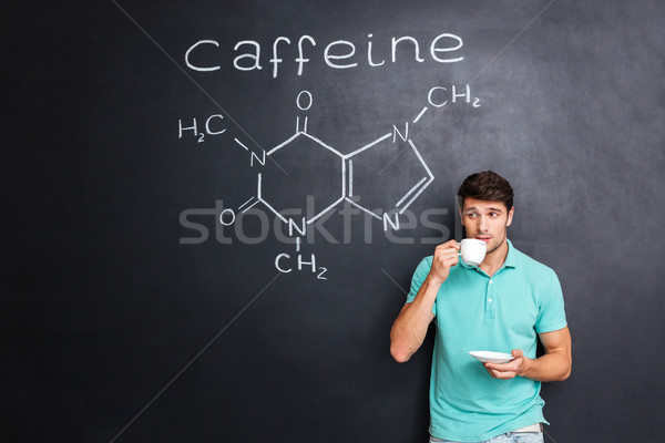 Man drinking coffee over blackboard with structure of caffeine molecule Stock photo © deandrobot