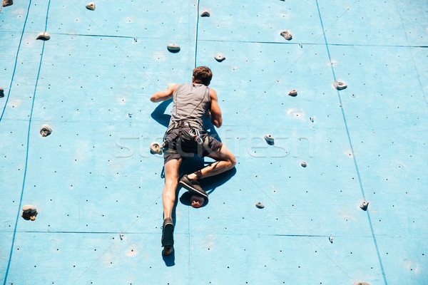 Young man doing exercise in mountain climbing on practice wall Stock photo © deandrobot