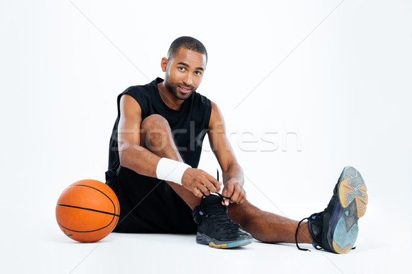 Handsome young man basketball player sitting and tying laces Stock photo © deandrobot