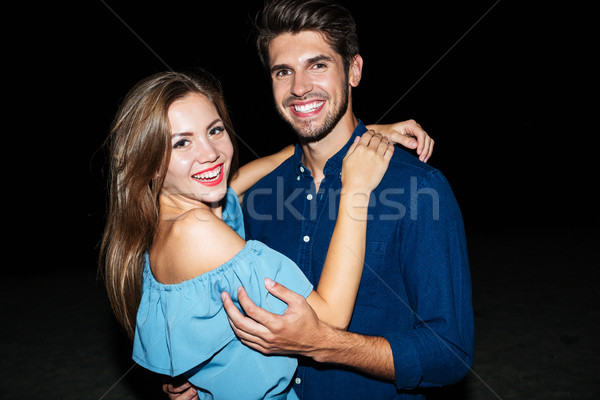 Cheerful beautiful young couple standing on the beach at night Stock photo © deandrobot