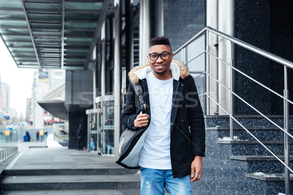 Young african man wearing backpack walking on the street Stock photo © deandrobot