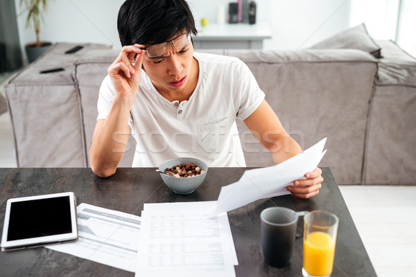 Young asian man working and eating Stock photo © deandrobot