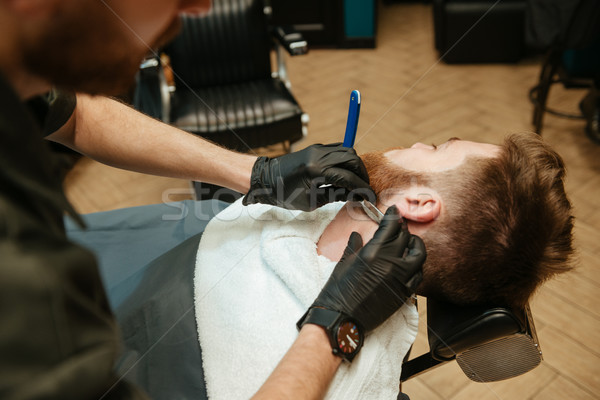 Man getting beard shaving while lies in chair at barbershop Stock photo © deandrobot