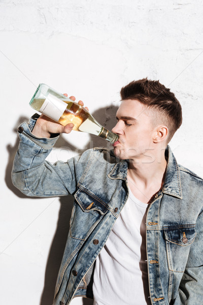 Handsome man standing on floor drinking alcohol Stock photo © deandrobot