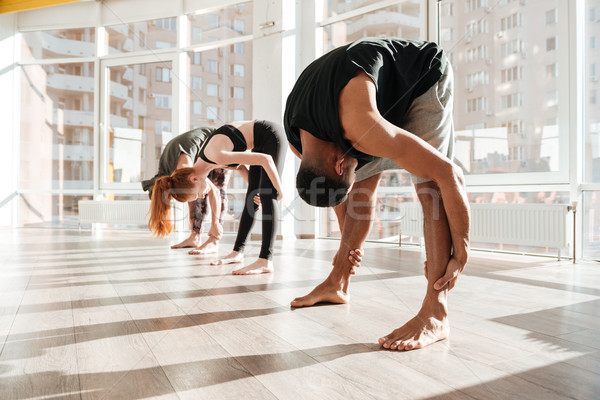 Group of people standing and warming up using yoga pose Stock photo © deandrobot