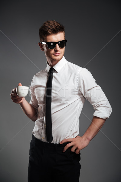 Successful businessman in formalwear holding cup of coffee while standing Stock photo © deandrobot