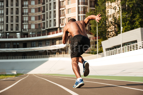 Back view of afro american sprinter starting on the running trac Stock photo © deandrobot