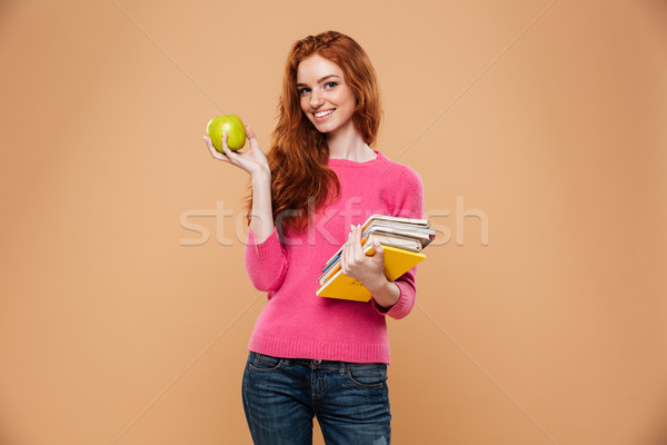 Portrait of a cheery pretty redhead girl holding apple Stock photo © deandrobot
