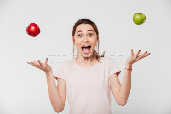 Portrait of a happy girl throwing apples in the air Stock photo © deandrobot