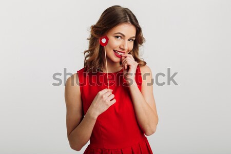 Portrait of a silly pretty girl holding fake lips at her face Stock photo © deandrobot