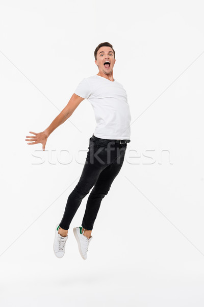 Full length portrait of a joyful man in white t-shirt Stock photo © deandrobot