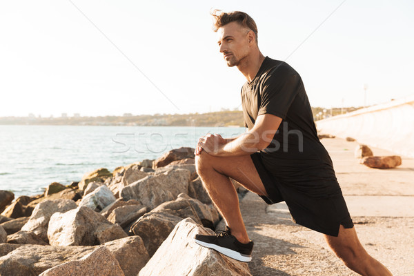 Portrait of a handsome sportsman doing stretching exercises Stock photo © deandrobot