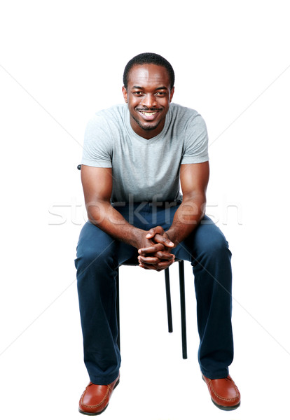 Portrait of a happy african man sitting on the chair over white bakground Stock photo © deandrobot