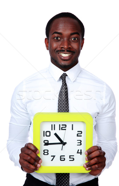 Time is money! Handsome african man holding a clock over white background Stock photo © deandrobot