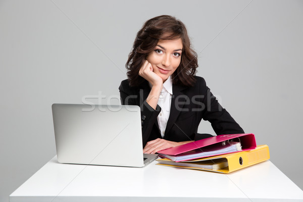 Beautiful smiling business woman using laptop and binders Stock photo © deandrobot