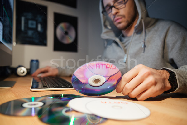 Stock photo: Thoughtful software developer in hoodie choosing CD with database