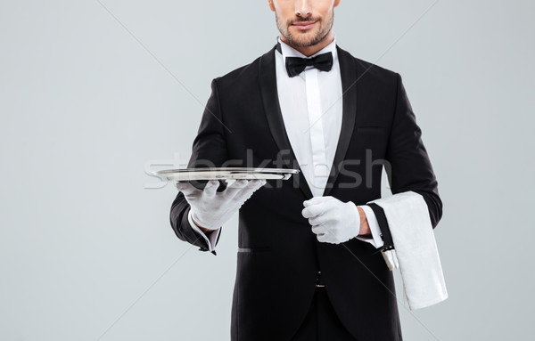 Waiter in tuxedo holding metal empty tray and napkin Stock photo © deandrobot