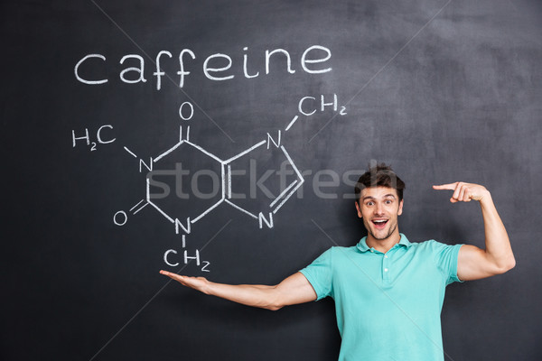 Cheerful young teacher pointing on chemical structure of caffeine molecule Stock photo © deandrobot