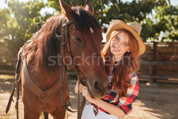 Smiling pretty young woman cowgirl in hat with her horse Stock photo © deandrobot