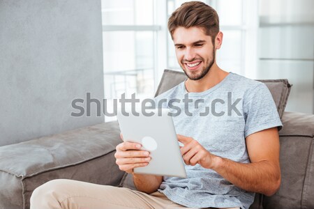 Cheerful man communication by tablet while drinking a coffee Stock photo © deandrobot