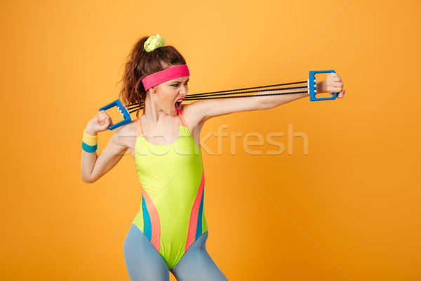 Strong young woman athlete shouting and exercising with expander Stock photo © deandrobot