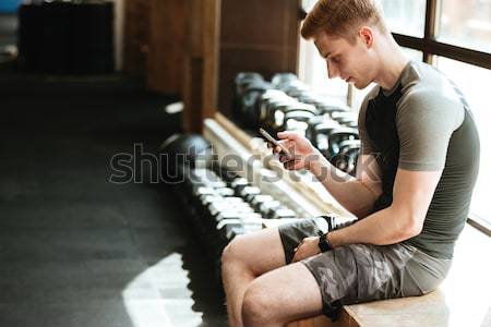 Sportos férfi evezés gép tornaterem sport Stock fotó © deandrobot