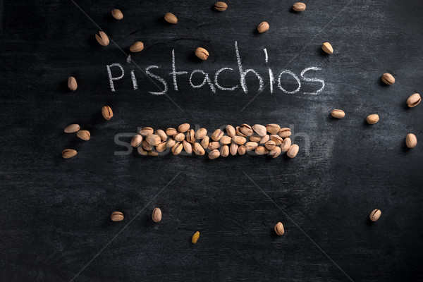 Pistachios over dark chalkboard background Stock photo © deandrobot