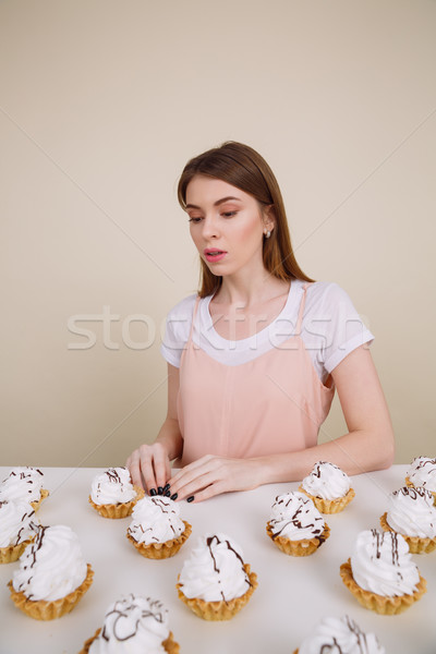 Serious young lady sitting and posing near cupcakes Stock photo © deandrobot