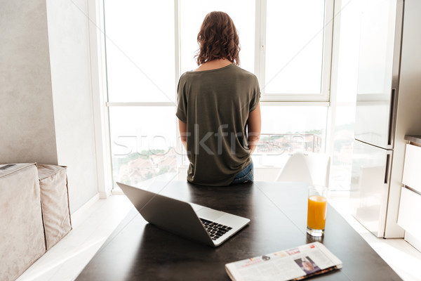 Back view of casual woman standing near table Stock photo © deandrobot