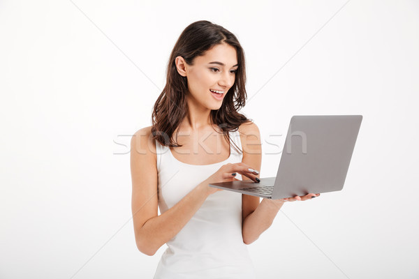 Portrait of a pretty girl dressed in tank-top using laptop Stock photo © deandrobot