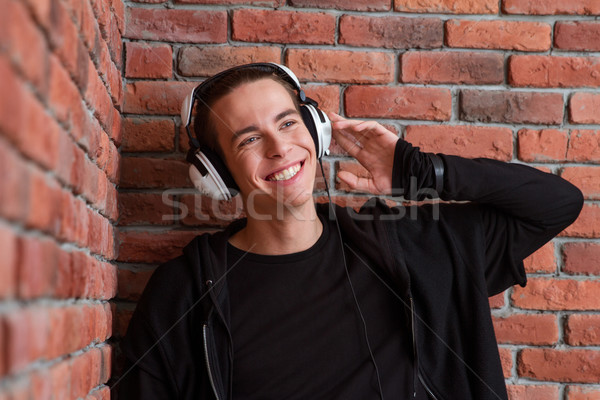 Smiling casual man listening music in headphones Stock photo © deandrobot