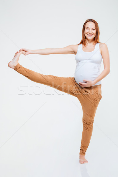 Smiling pregnant woman stretching leg  Stock photo © deandrobot