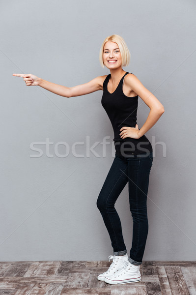 Stock photo: Full length of smiling young woman standing and pointing away