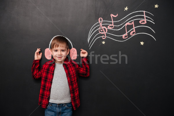 Kid listening to music over black chalk board with drawings Stock photo © deandrobot