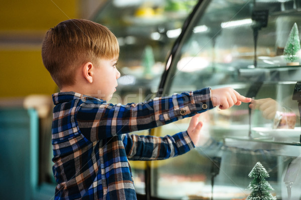 Little boy choosing and pointing at cake in showcase Stock photo © deandrobot