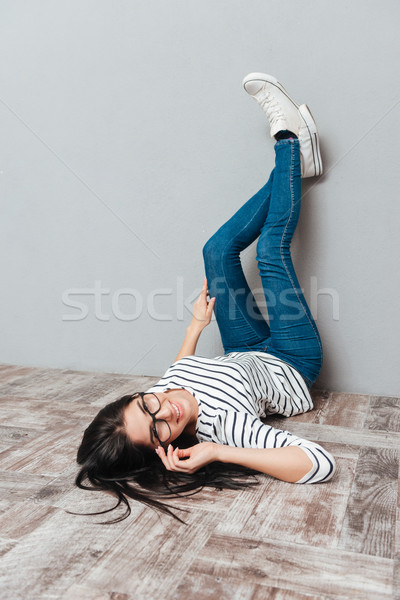 Young woman lies on floor over grey background Stock photo © deandrobot