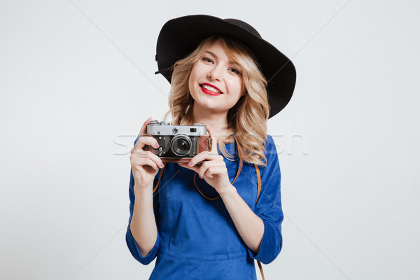 Happy woman dressed in blue dress wearing hat holding camera Stock photo © deandrobot