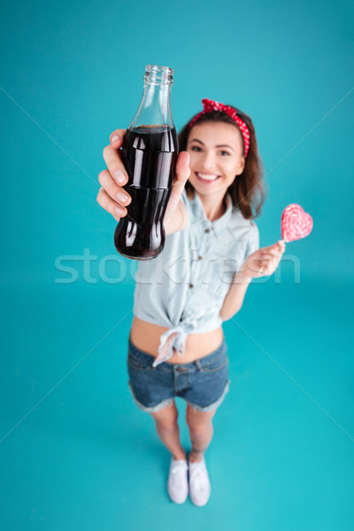 Smiling young lady holding aerated sweet water. Focus on water. Stock photo © deandrobot