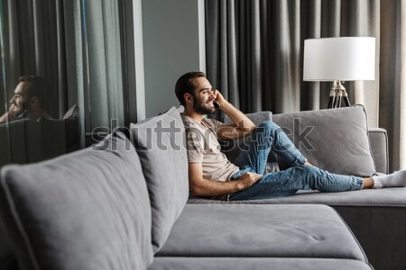 Businessman using smartphone while lying on a bed Stock photo © deandrobot