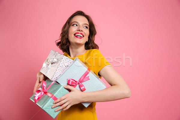 Cheerful young woman in yellow dress holding heap of presents Stock photo © deandrobot