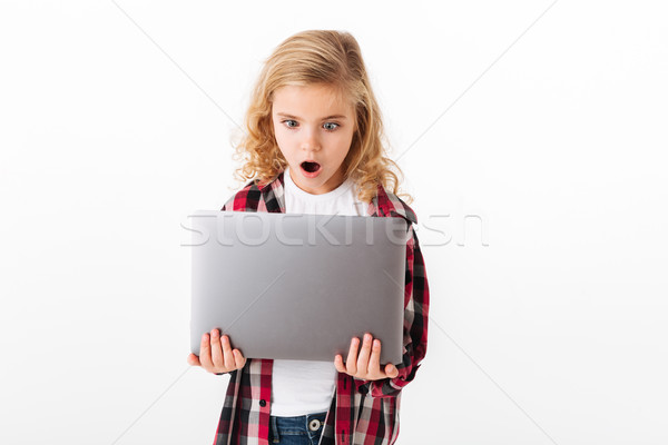 Portrait of an astonished little girl looking at laptop Stock photo © deandrobot